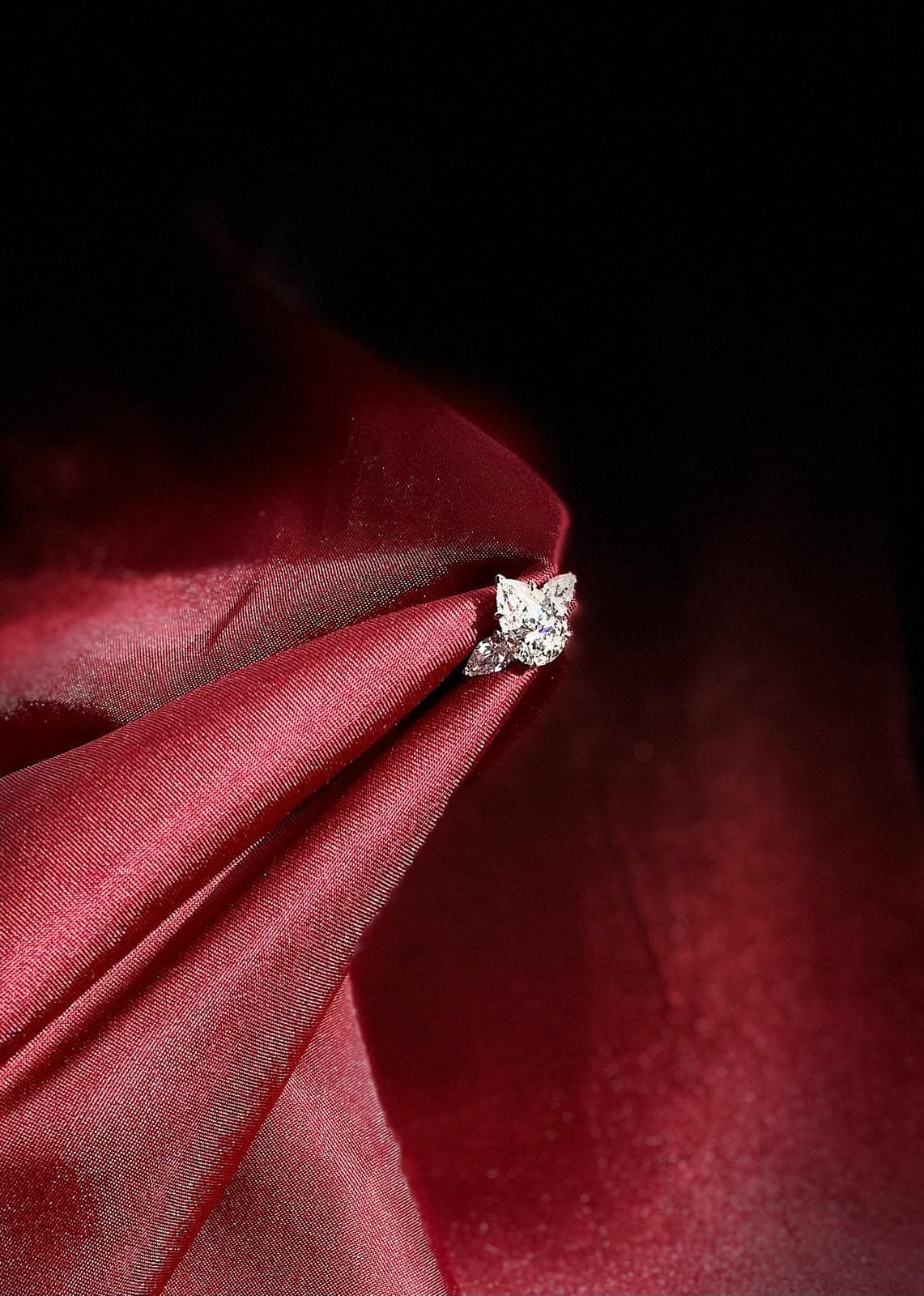 A Luméa lab grown diamond ring resting on burgundy silk